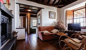 A cozy living room with a fireplace, a sofa, a television, and a dining area.