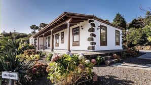 A traditional white building with a tiled roof, stone accents, and a covered porch.
