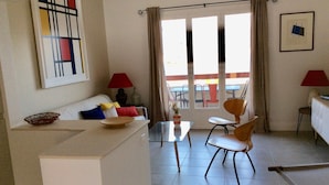 A living room with a sofa, a coffee table, two chairs, a small table with a vase, and a view through a glass door. - Charming air-conditioned apartment with sea view terrace (Tiuccia)