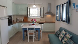 Een kleine keuken met een eettafel, stoelen, een bank en een raam met gordijnen.