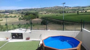 A wooden hot tub on a balcony with a view of a rural landscape.