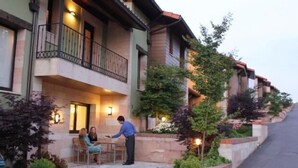 Un hotel con balcón, mobiliario exterior y fachada bien iluminada.