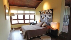 Un dormitorio con cama, mesitas de noche, lámpara y ventana.