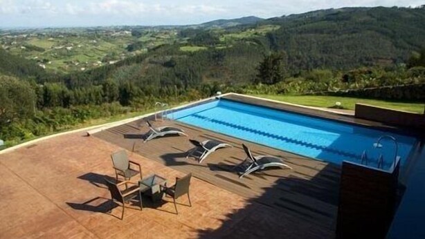 Una piscina con sillones de descanso y vistas a un paisaje montañoso.