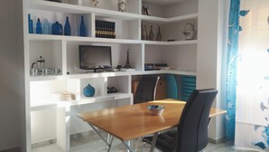 A modern room with a wooden dining table, black chairs, and a white shelving unit with various decorative items. - Nevada Apartaments, between Granada and Sierra Nevada (Cenes de la Vega)