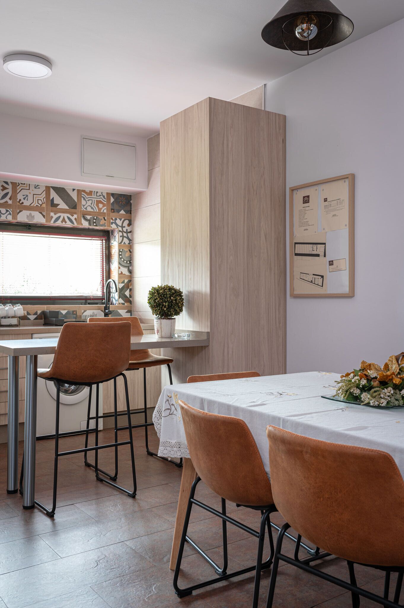 Una cocina moderna con comedor, que incluye un armario de madera, una planta en maceta y un tablón de anuncios.