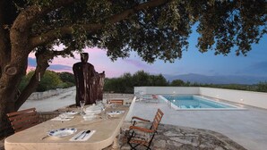 An outdoor dining area with a pool and a view of the mountains. - Secluded Villa Dubrava, private pool, olive grove surrounds the villa, Brac Island (Pučišća)