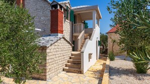 A stone building with a red brick chimney, a white exterior, and a staircase leading to a balcony. - Secluded Villa Dubrava, private pool, olive grove surrounds the villa, Brac Island (Pučišća)