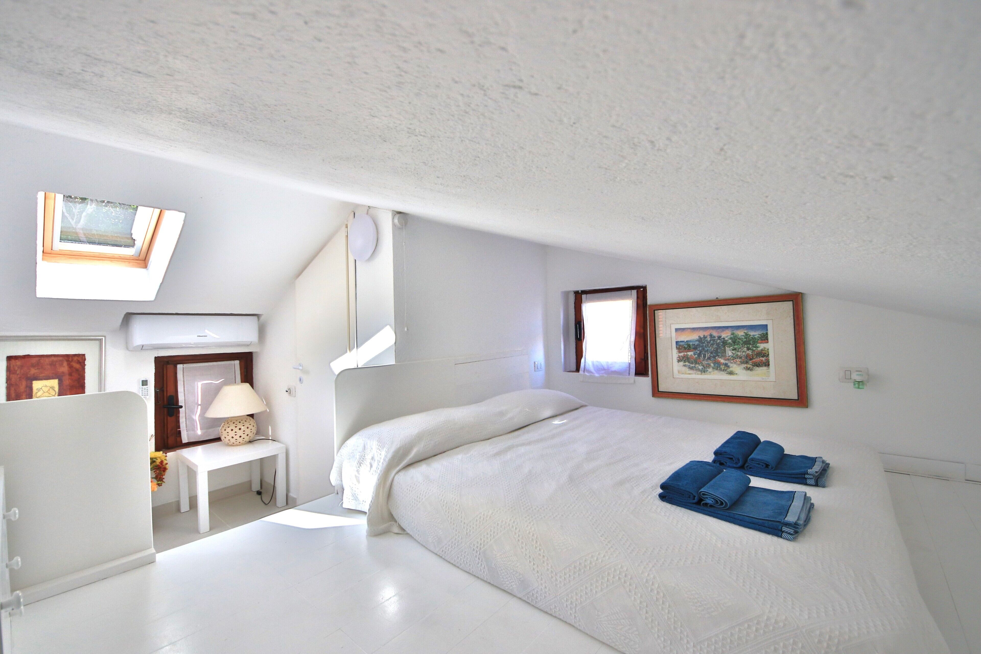 Un dormitorio con una cama, un escritorio, una lámpara y un cuadro en la pared.