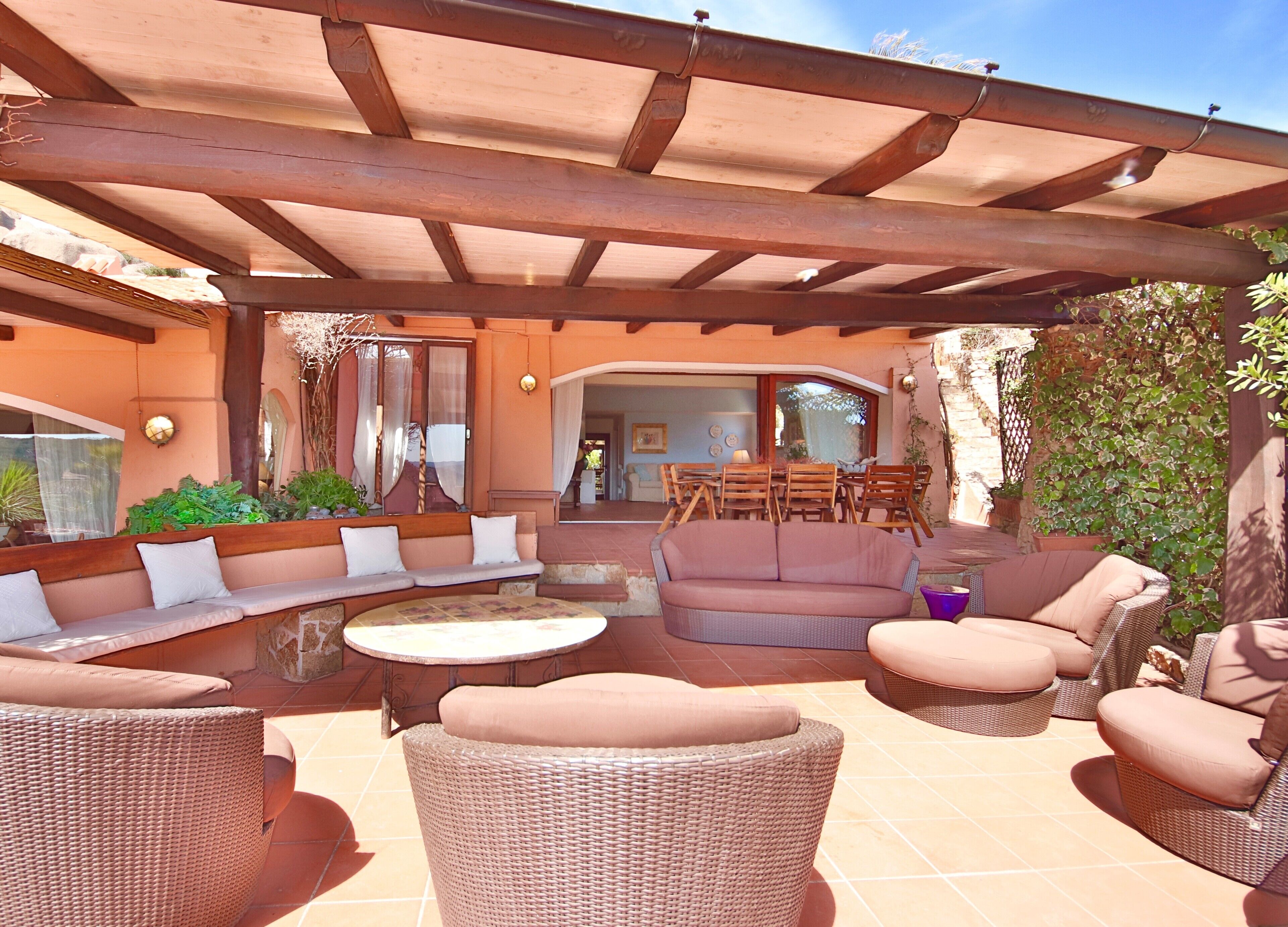 Un patio al aire libre con mobiliario de mimbre, una zona cubierta y una mesa de comedor.