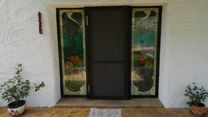 A door with stained glass panels, a potted plant on the left, and a potted plant on the right.