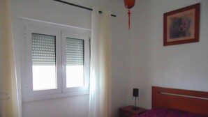A bedroom with a bed, a window with blinds, a nightstand, and a wall-mounted lamp. - WELL ME WANT 1, apartment with pool 5km from Lisbon and Costa da Caparica (Feijó)