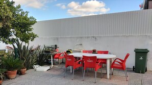 An outdoor patio with a round table and red chairs, surrounded by potted plants and a white wall. - WELL ME WANT 1, apartment with pool 5km from Lisbon and Costa da Caparica (Feijó)