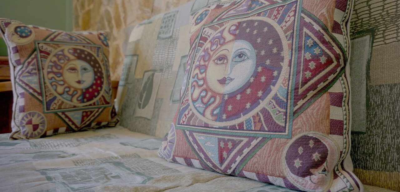 Two pillows with intricate designs on a bed.