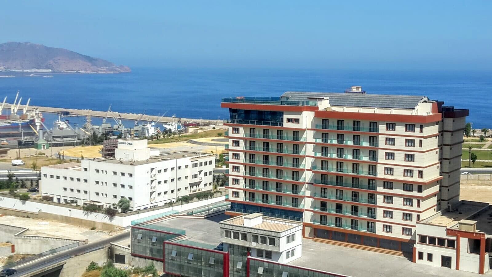 A multi-story hotel with a modern design, featuring a prominent glass facade and a rooftop terrace.