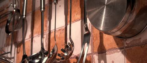 Una cocina con utensilios de acero inoxidable colgados en la pared.
