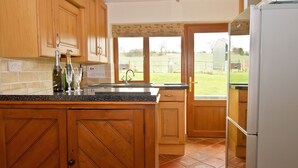 A kitchen with wooden cabinets, a countertop, a sink, and a refrigerator. - Coach House at Oaks Barn Farm, optional salt water hot tub near to Stratford. (Alcester)