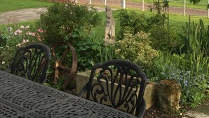 A garden with a statue, a table, and chairs. - Coach House at Oaks Barn Farm, optional salt water hot tub near to Stratford. (Alcester)