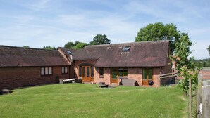 A brick building with a sloped roof, a small window, and a door. - Coach House at Oaks Barn Farm, optional salt water hot tub near to Stratford. (Alcester)