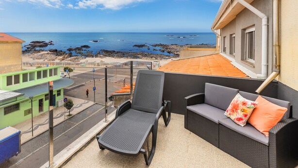 Un balcón con vista al mar, un sofá y una silla.