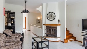 Una sala de estar con chimenea, escalera y televisor.