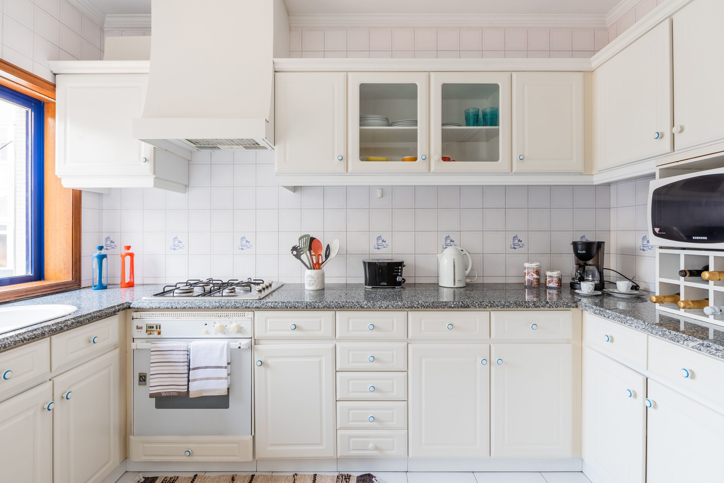 A modern kitchen with white cabinetry, a gas stove, a built-in oven, and a microwave.