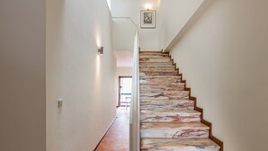 Una escalera con escalones de mármol y barandillas de madera que lleva a un cuarto con una puerta al final.