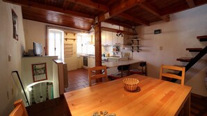 Een gezellige keuken met houten balken, een eettafel, stoelen en een klein eiland met een spoelbak.