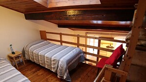 Een slaapzaal met twee bedden, een dakraam, houten vloeren en een kleine trap.