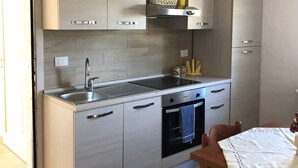 A modern kitchen with light wood cabinets, a stainless steel sink, and a built-in oven.