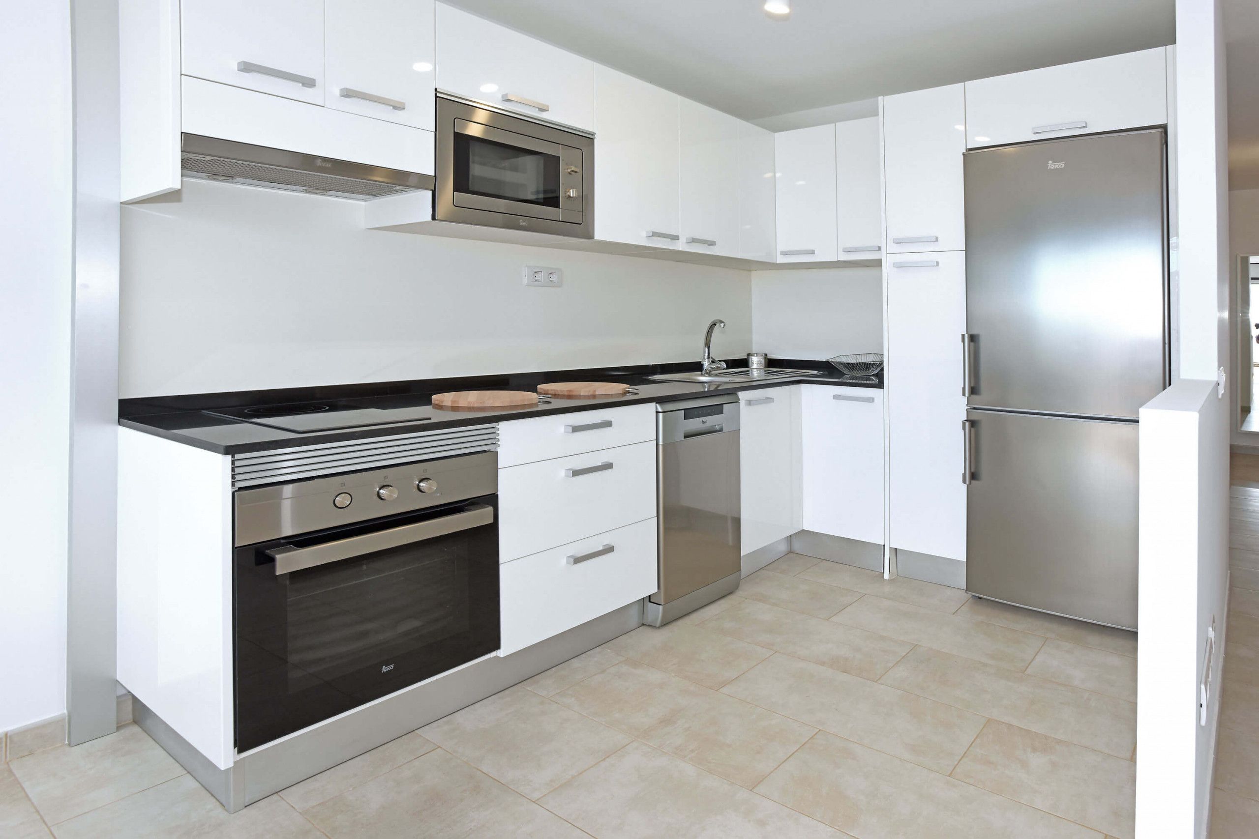 A modern kitchen with white cabinets, stainless steel appliances, and a black countertop.