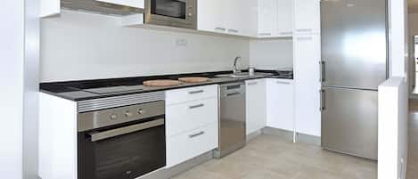 A modern kitchen with white cabinets, stainless steel appliances, and a black countertop.