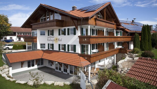 A large, two-story hotel with a sloped roof, multiple balconies, and a sign indicating it is a "Landhotel." - Landhotel Haflingerhof (Rosshaupten)