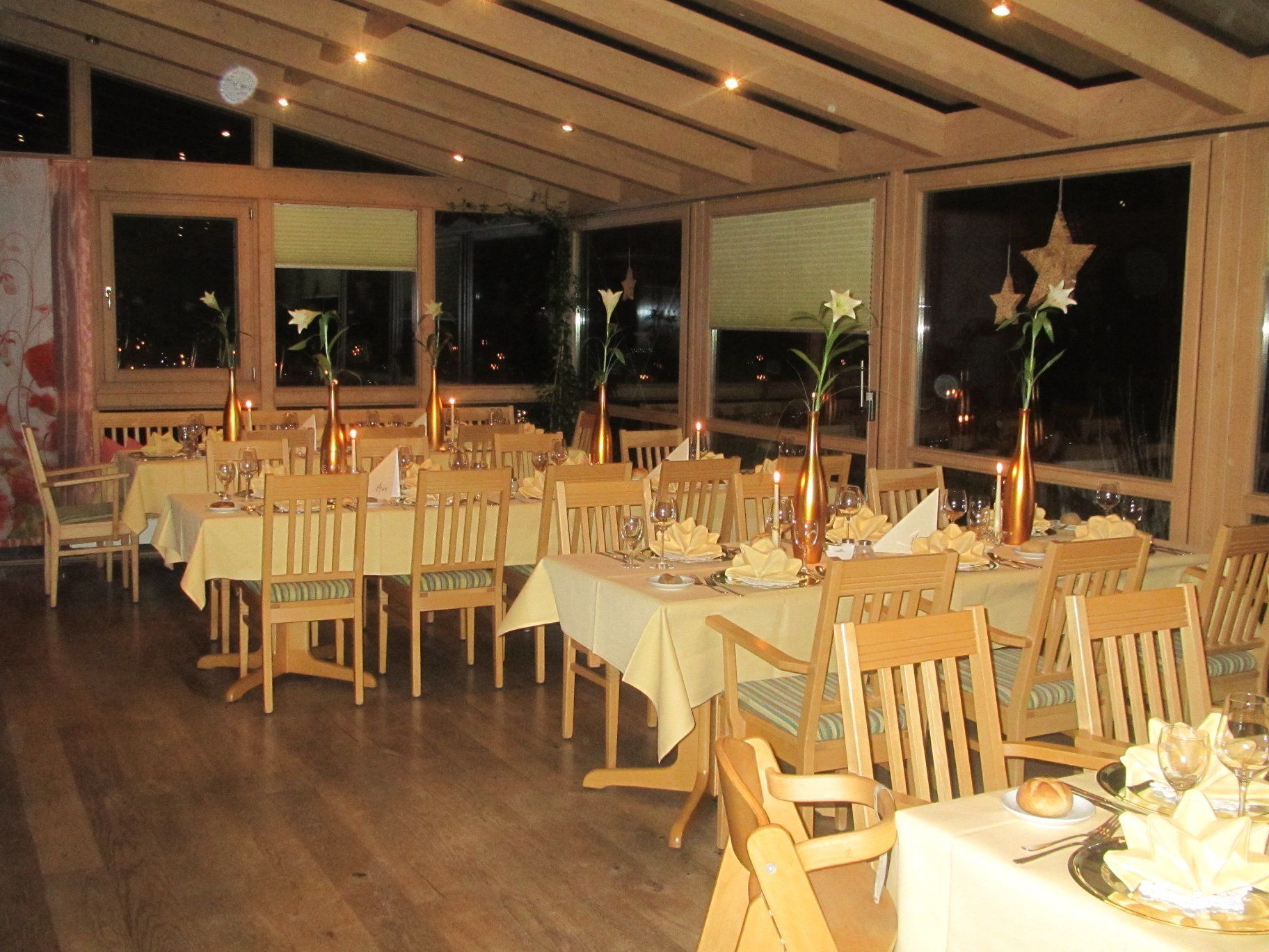 Un restaurant amb taules i cadires de fusta, espelmes i grans finestres.