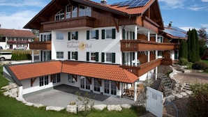 Un hôtel à deux étages, doté d’une façade en bois, de volets verts et d’une enseigne indiquant « Landhotel Haflinger Hof ».
