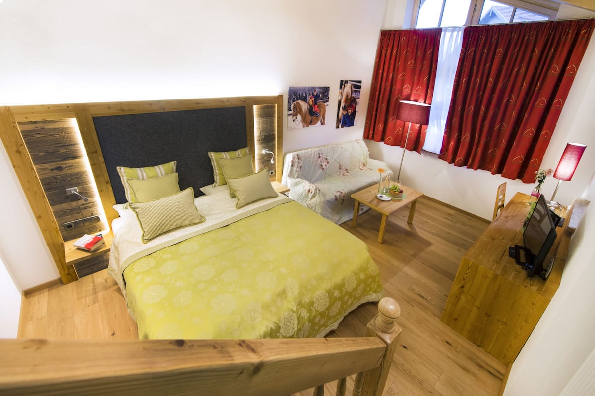 A bedroom with a bed, a sofa, a desk, and a TV.