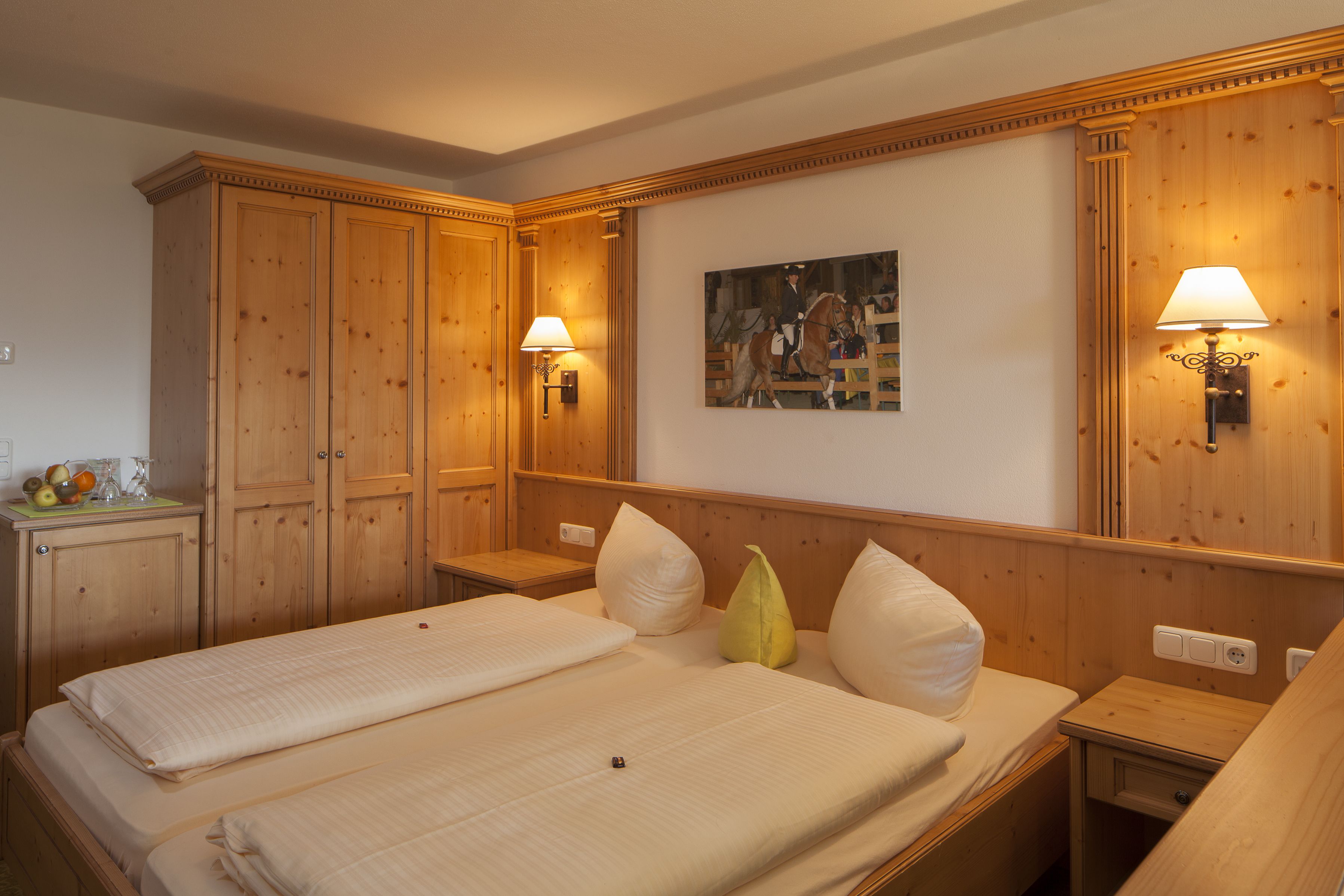 Habitació d'hotel amb dos llits, panells de fusta, un quadre a la paret i làmpades penjades a la pared.