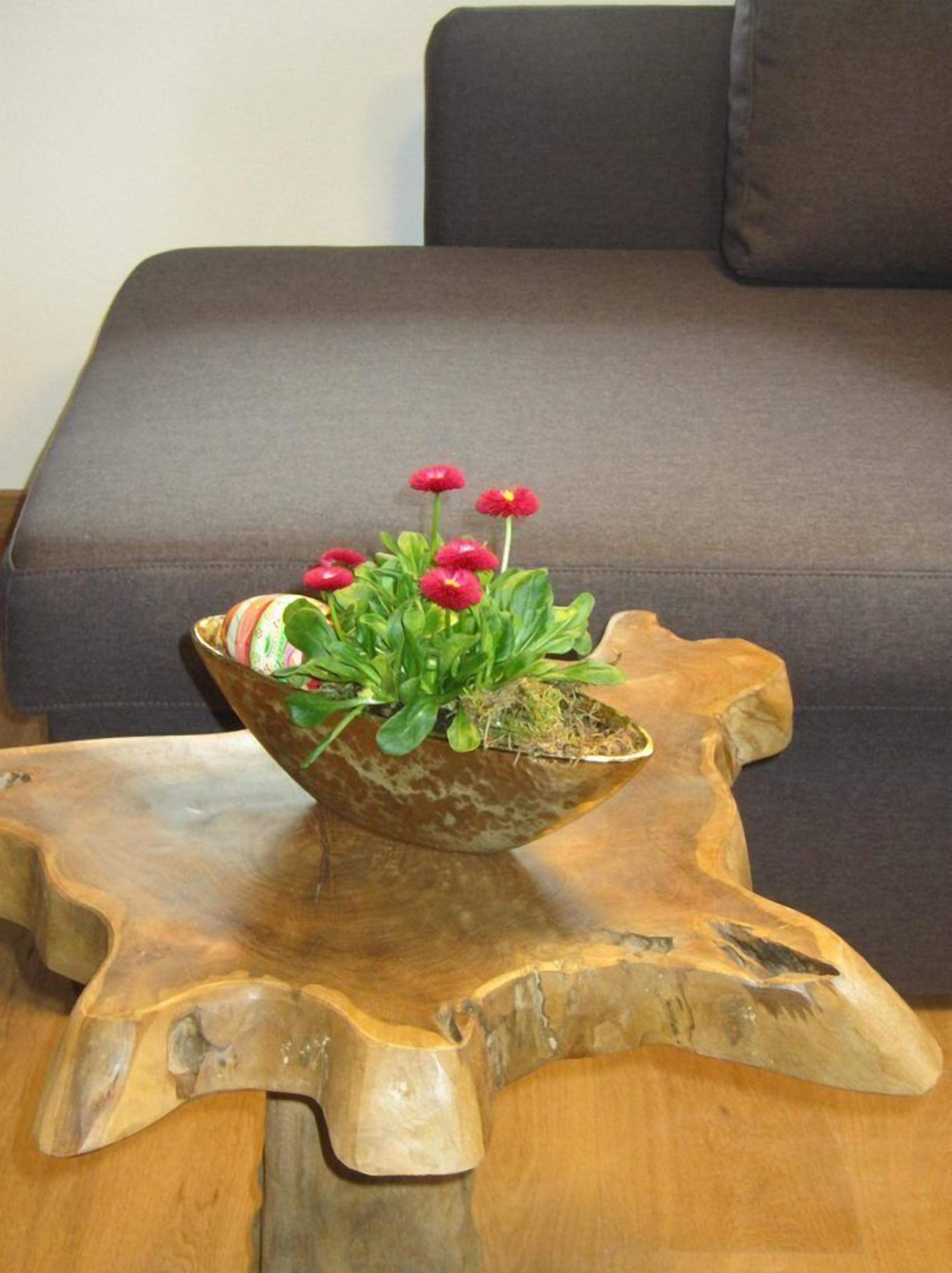 Un tavolo a forma di ciotola in legno con una pianta in vaso e fiori.