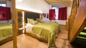 Une chambre à coucher avec une tête de lit en bois, un lit avec une literie verte, une table de chevet et un escalier en bois.