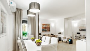 A modern, well-lit living room with a dining area, featuring a white table, chairs, and a large window with curtains. - The best in Rome PRESTIGE VINE  (Roma)