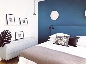 A modern bedroom with a blue accent wall, a white bed, and a minimalist dresser. - Dum House & Spa: Nice old town (Nice)