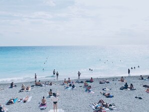 A beach with people sunbathing and swimming.