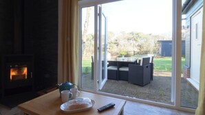 Ein gemütliches Wohnzimmer mit Kamin und einer Schiebetür zu einer Terrasse mit Gartenmöbeln.