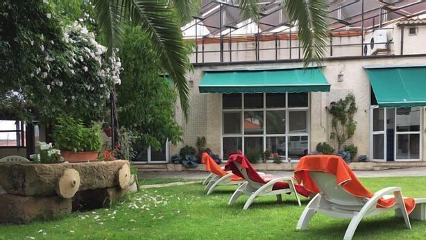 Un patio con mobiliario exterior y un edificio al fondo.