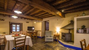 Un comedor con suelo de piedra, mobiliario de madera y chimenea.