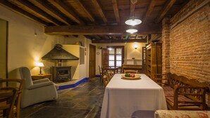 Un comedor rústico con suelo de piedra, mobiliario de madera y chimenea.