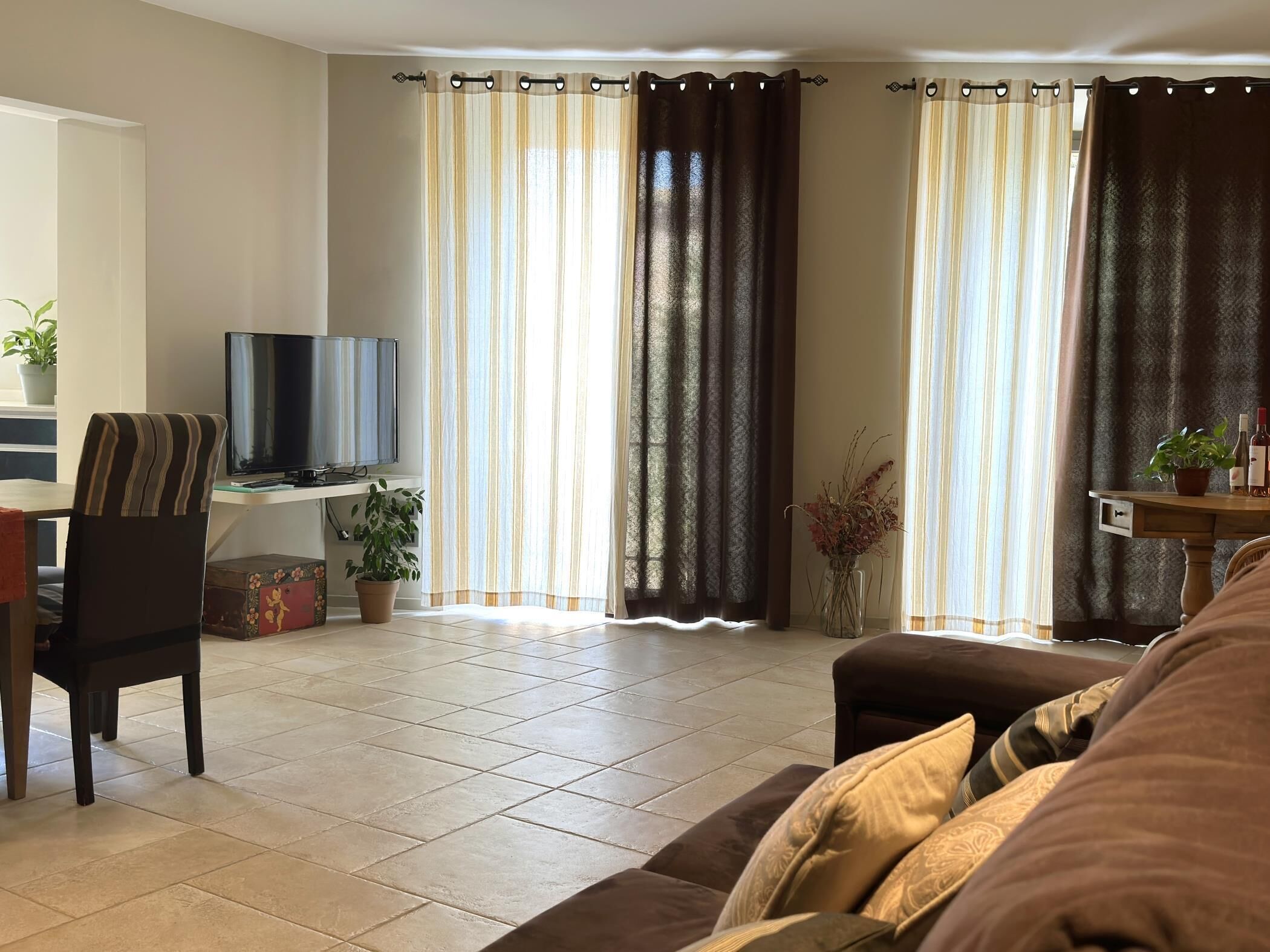Een woonkamer met een bank, een televisie, een bureau en gordijnen.