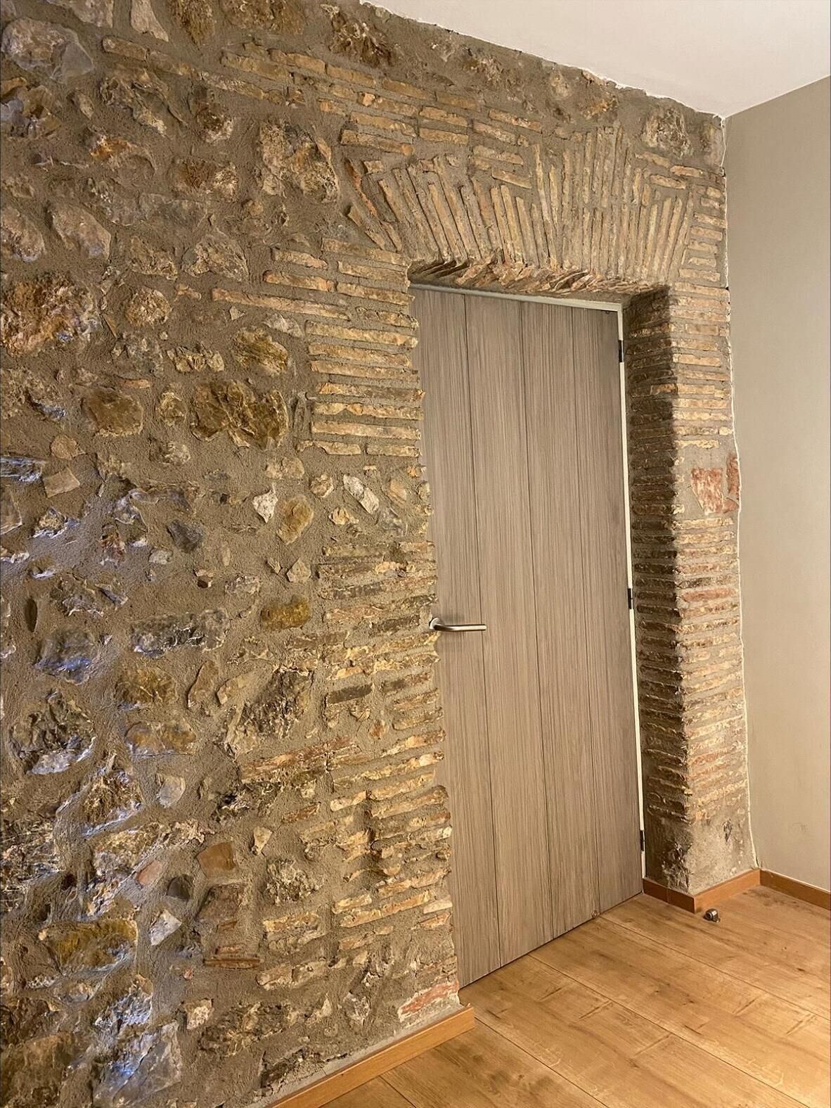 Ein Zimmer mit einer Steinwand und einer Holztür.