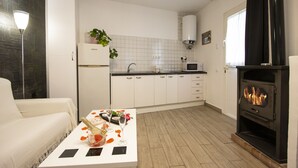 Une cuisine moderne avec des meubles blancs, un four encastré et un poêle à bois noir.