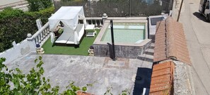 Un espace piscine aménagé sur le toit, avec un petit auvent, des chaises longues et un jacuzzi.